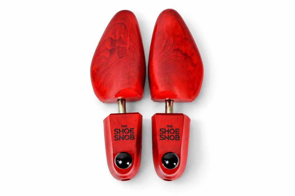A pair of red wooden shoe trees labeled "THE SHOE SNOB," featured in a guide to shoe trees.