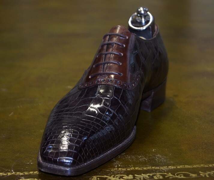 Elegant brown crocodile leather dress shoe with a polished finish and matching laces, displayed on a textured surface. Perfect for formal occasions and luxury fashion.