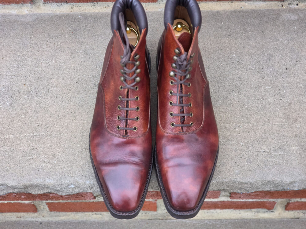 A pair of brown leather dress boots with laces and a rounded toe.
