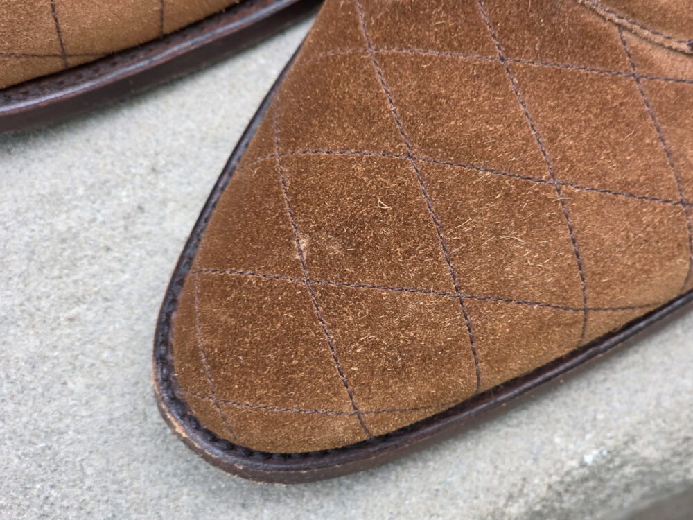 Close-up of a brown suede shoe with a quilted pattern on the toe.