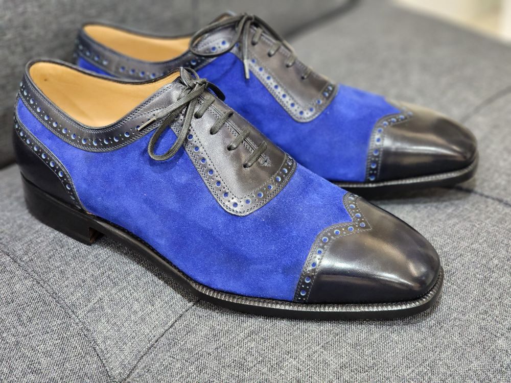 A pair of blue suede and black leather shoes, highlighting the "Shoe Industry Lies" theme.