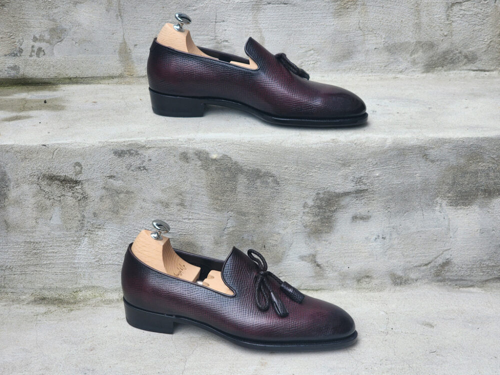 A pair of burgundy leather shoes with a textured finish and decorative laces, highlighting Shoe Industry Secrets.