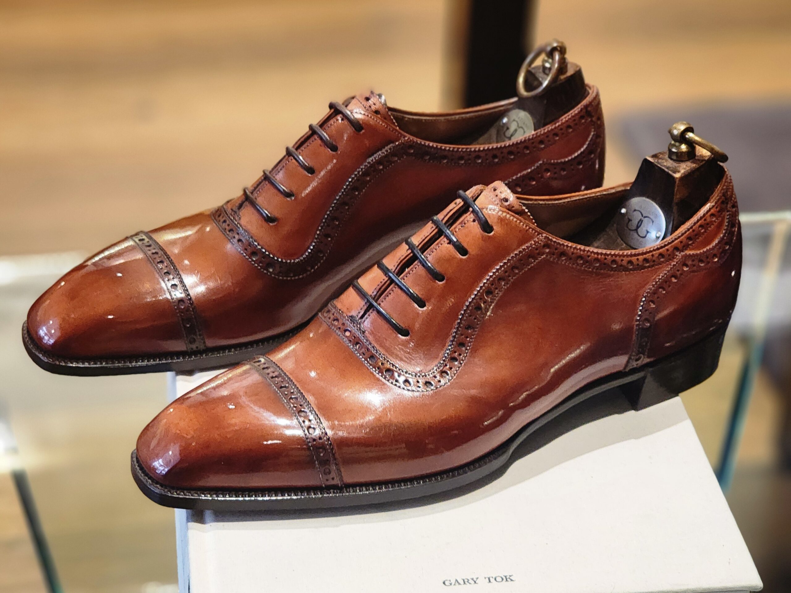 A pair of polished brown leather dress shoes with decorative broguing, highlighting the "Shoe Industry Lies" about quality craftsmanship.
