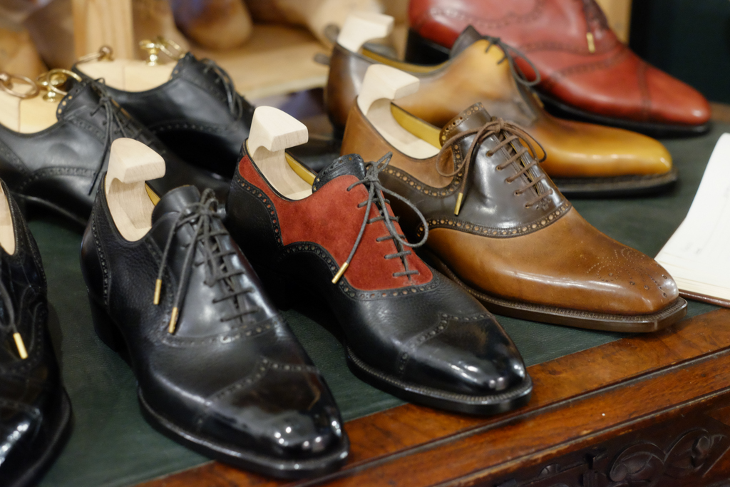 A variety of leather shoes in black, brown, and burgundy displayed with wooden shoe trees, highlighting the craftsmanship relevant to Shoe Industry Lies.