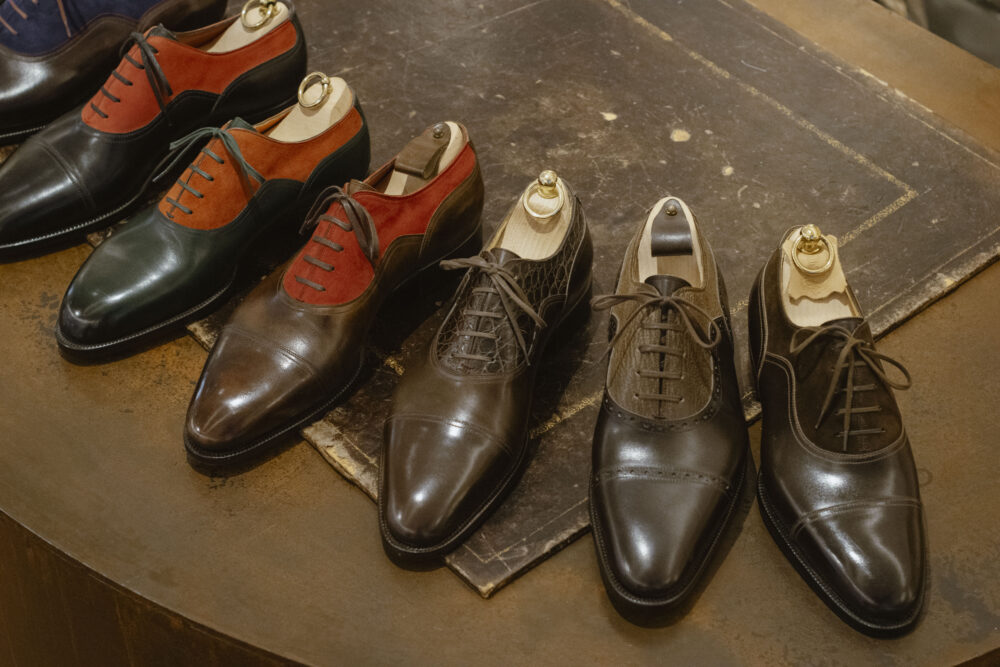 A selection of elegant shoes in various shades of brown, green, and red, highlighting craftsmanship related to Shoe Industry Lies.