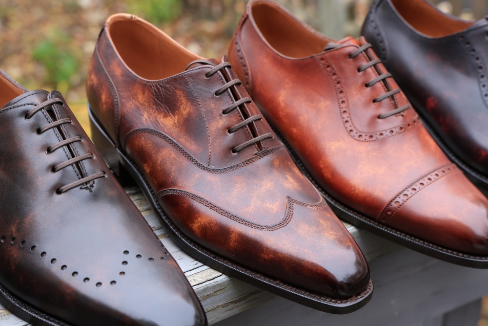 A close-up of four pairs of dress shoes in varying shades of brown, featuring smooth leather and lace-up designs.