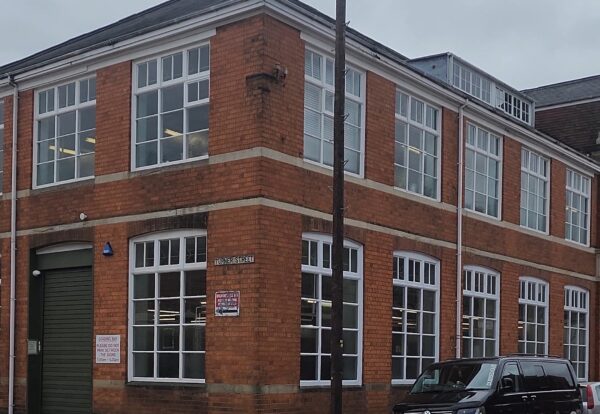 A red brick building with large windows and a green loading bay door, featuring a sign that reads "Turner Street."