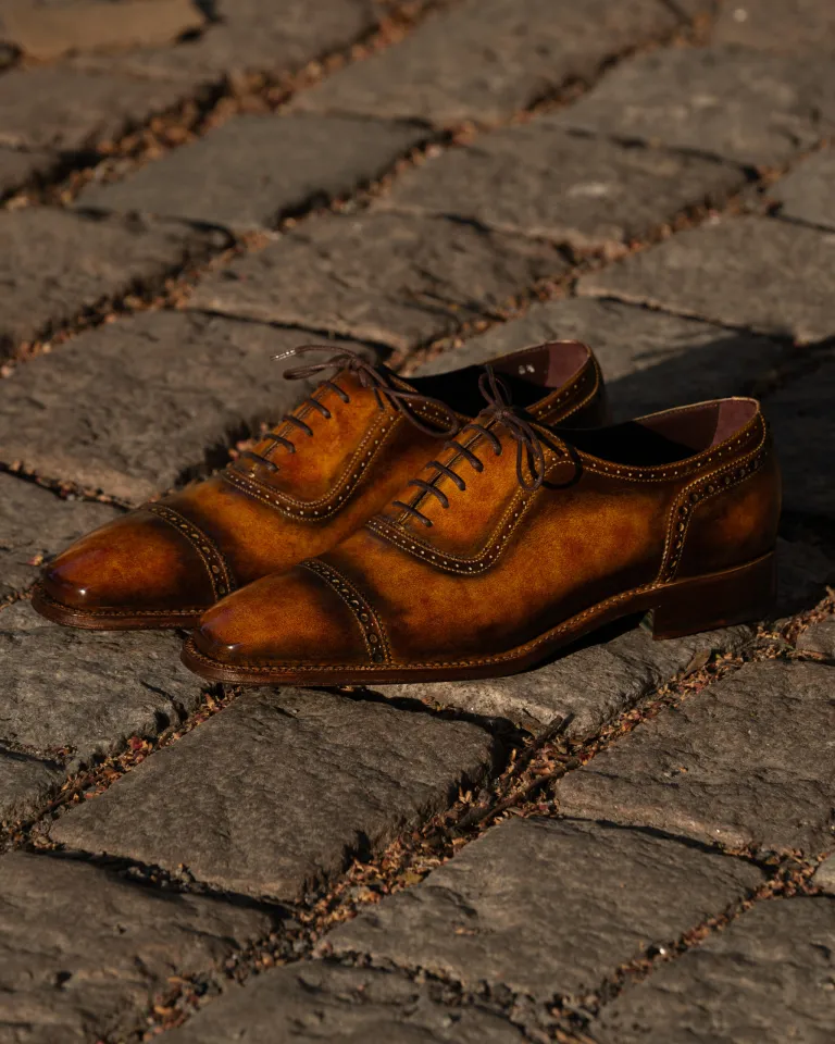A pair of polished brown leather dress shoes with intricate stitching.