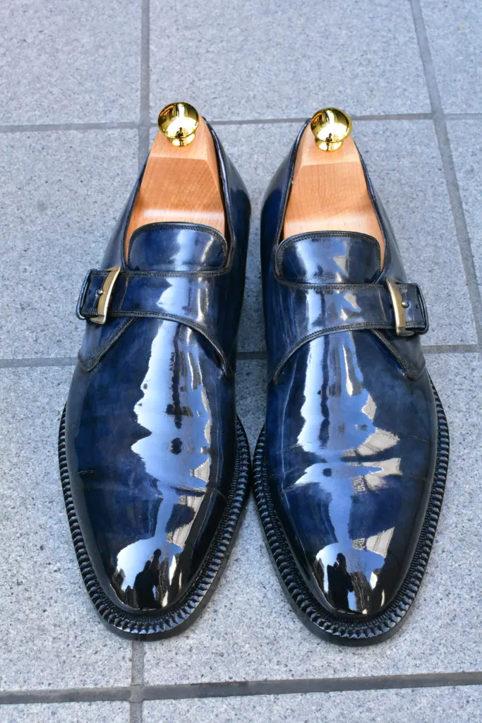 A pair of shiny navy blue leather shoes with a buckle detail for the shoe shining championships 2026 finalists