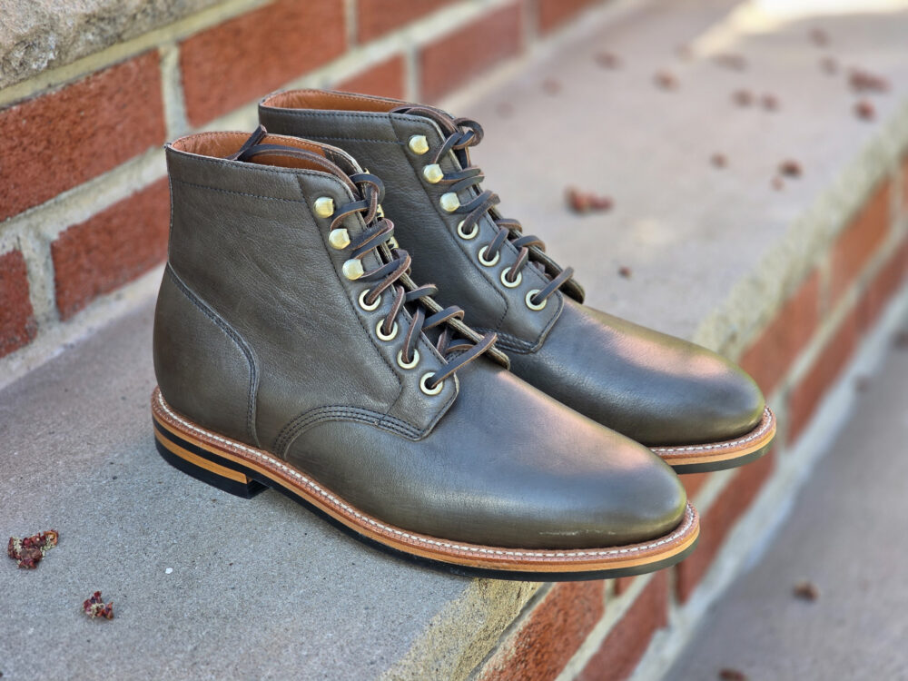 Brown leather lace-up boots with gold eyelets and a contrasting tan sole.