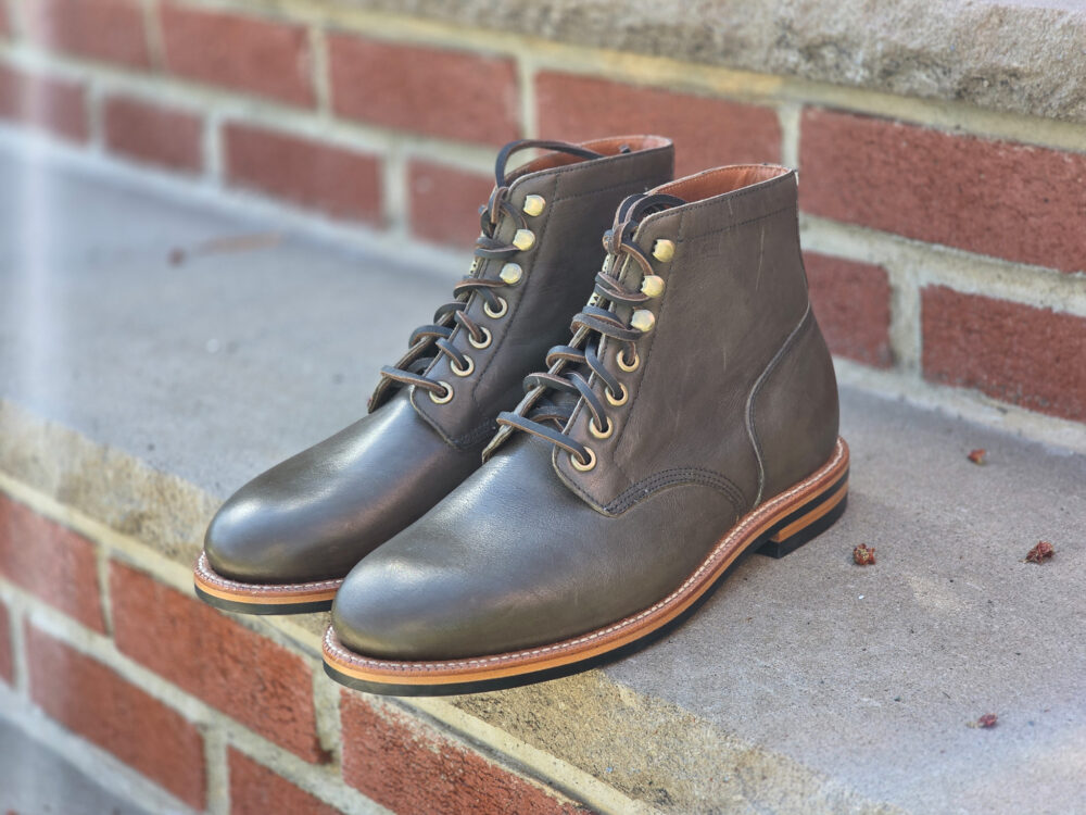 A pair of brown leather lace-up boots with gold eyelets and a tan sole.