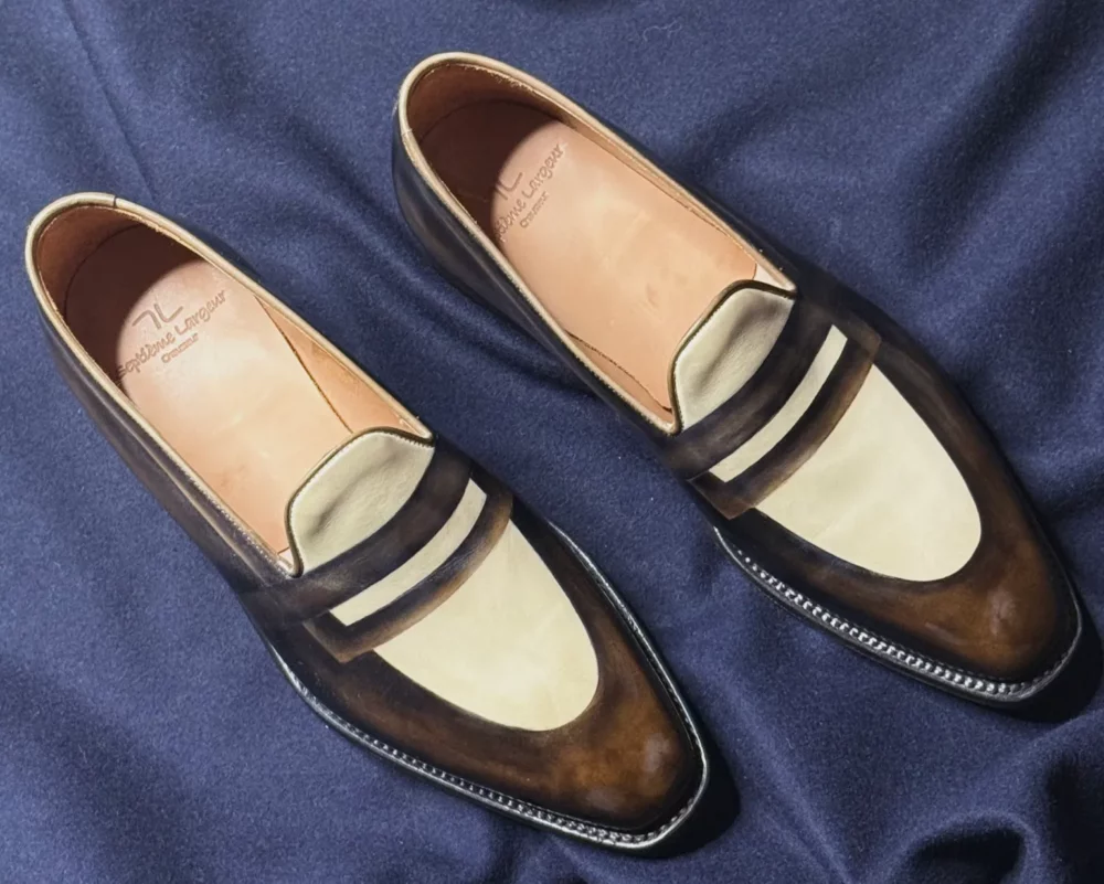 A pair of stylish brown and cream leather loafers with a sleek design.