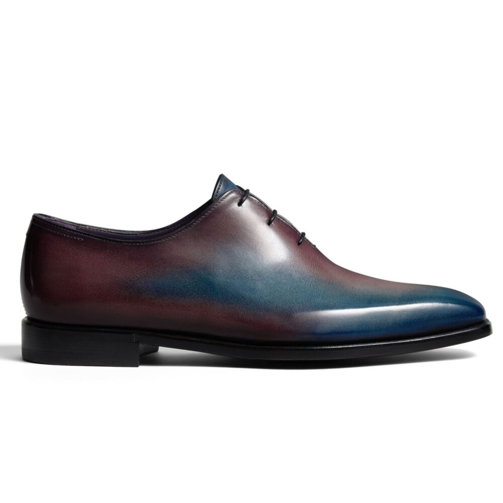 A sleek, gradient leather dress shoe featuring shades of deep burgundy and blue with a black sole.