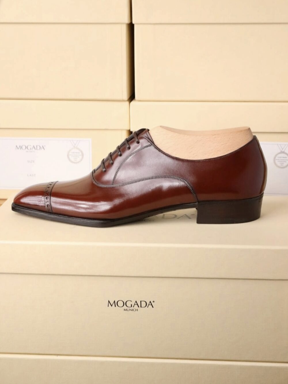 A polished brown leather dress shoe with a pointed toe and lace-up design.