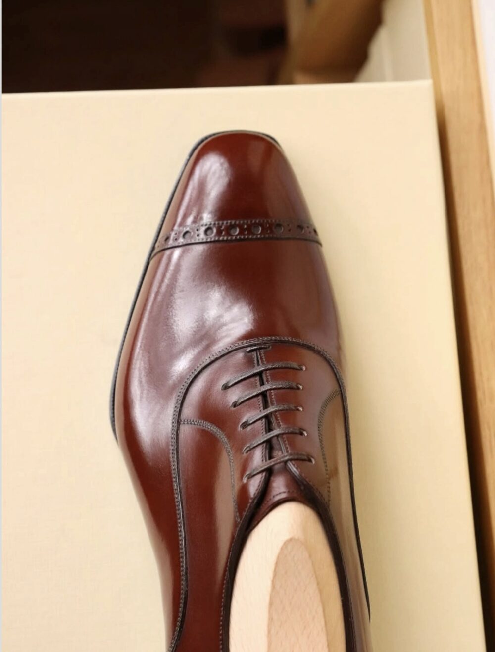 A polished brown leather dress shoe with decorative stitching and laces.