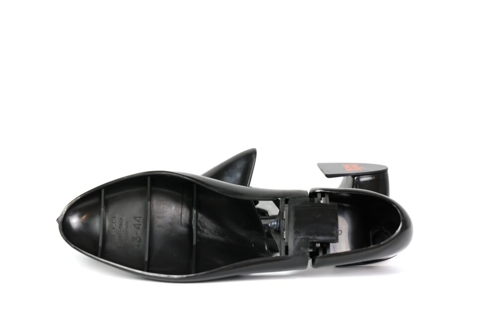 A black high-heeled shoe with a pointed toe and a visible interior mechanism.