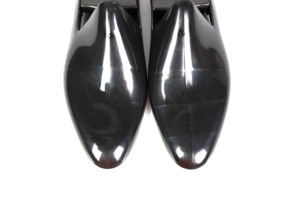 A pair of shiny black dress shoes viewed from above.