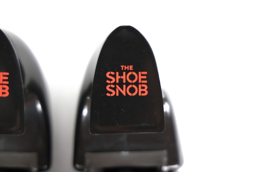 Two black shoehorns with the text "THE SHOE SNOB" in red on the ends.
