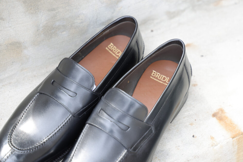 A pair of polished black leather loafers with brown insoles.