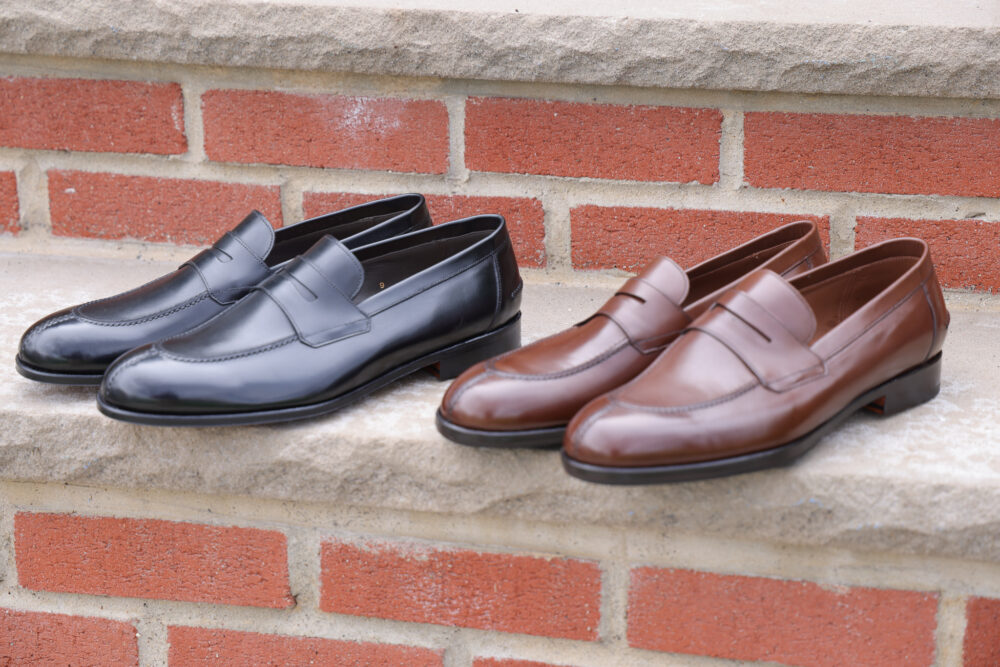 A pair of leather loafers, one black and one brown, displayed side by side.