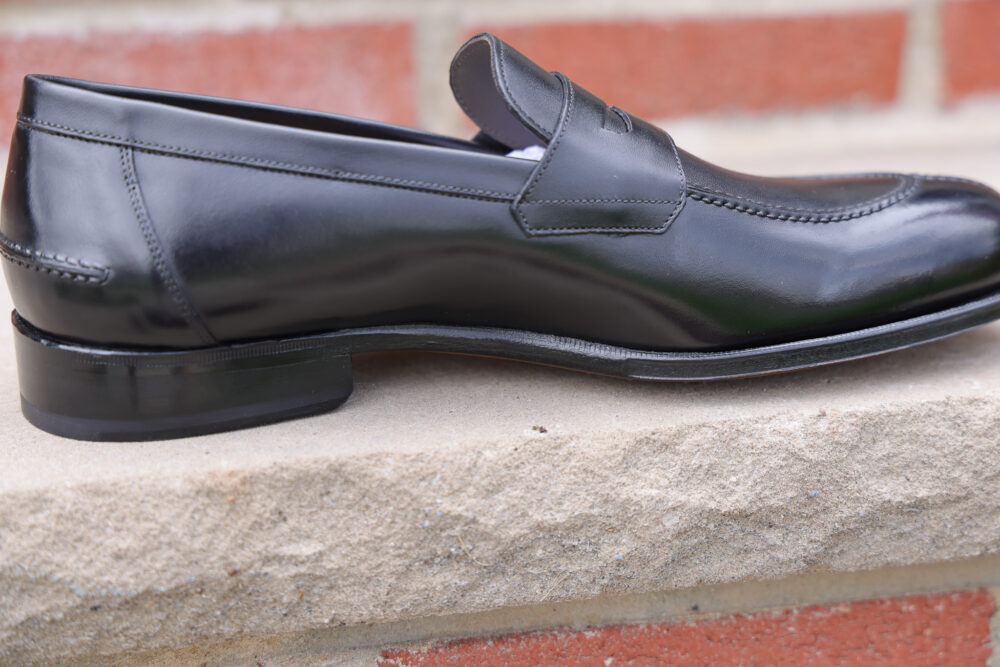 A black leather loafer shoe with a stitched design and a low heel.