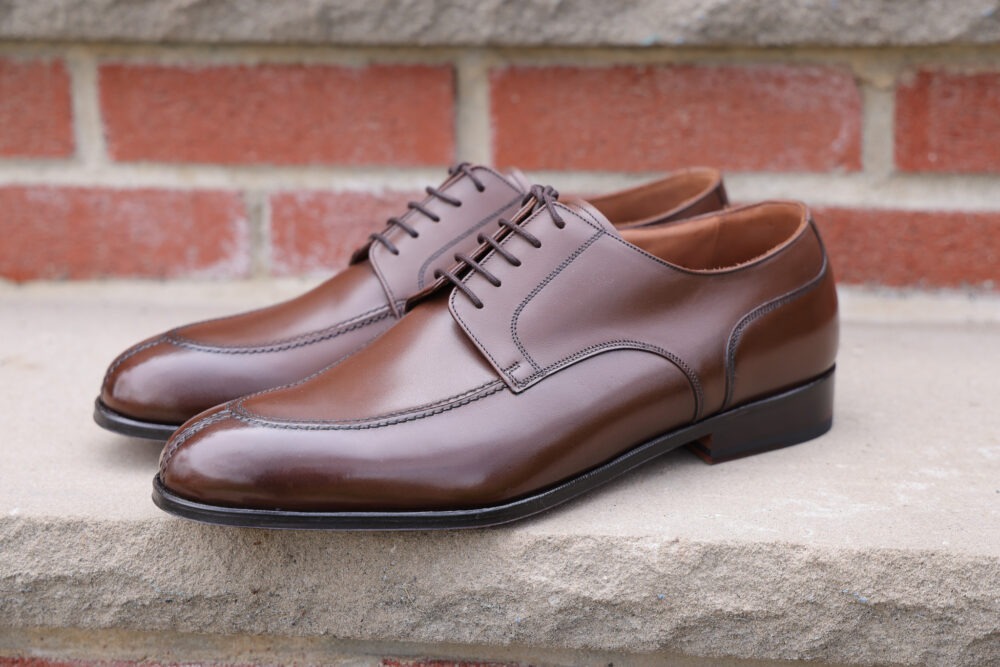 A pair of polished brown leather dress shoes with laces.