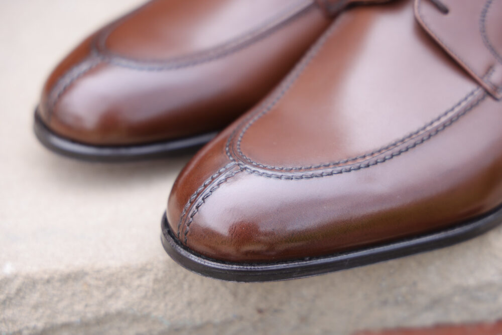 A close-up of polished brown leather dress shoes with decorative stitching.