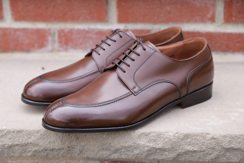 A pair of polished brown leather dress shoes with laces and a sleek design.