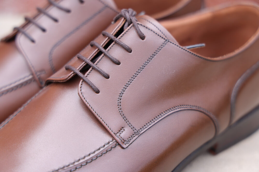 A close-up of polished brown leather dress shoes with dark brown laces.