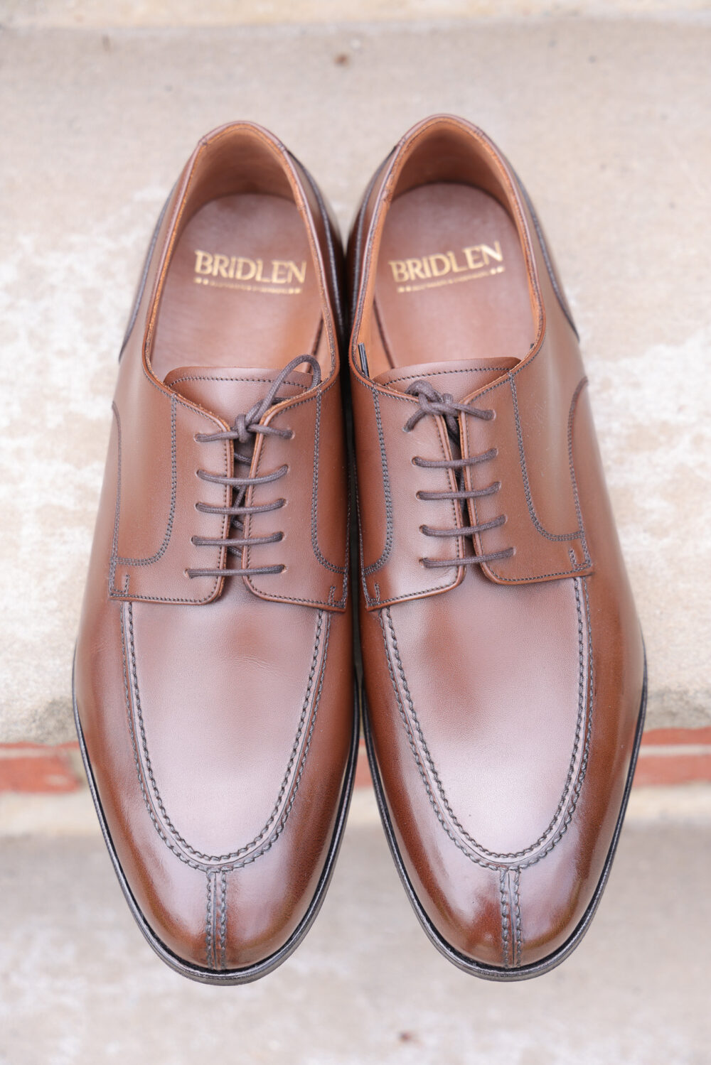 A pair of polished brown leather dress shoes with laces and subtle stitching details.