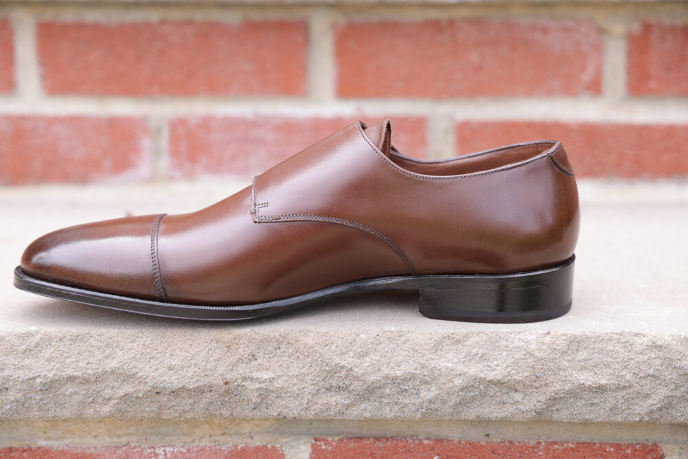 A brown leather dress shoe with a sleek design and a slightly pointed toe.