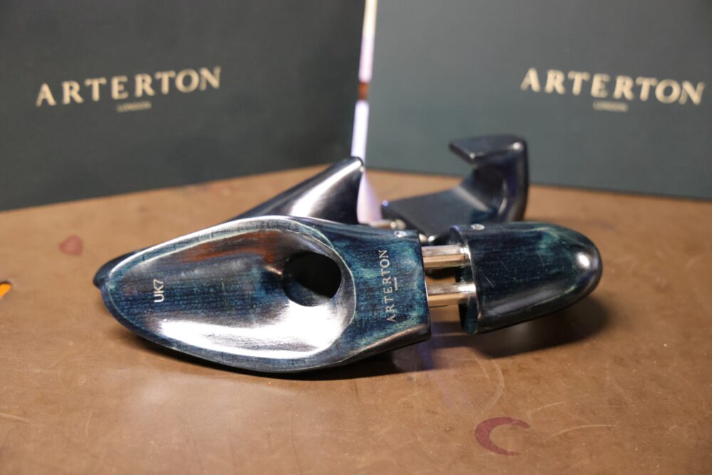 A pair of blue wooden shoe trees with metal fittings, labeled "UK7" and "ARTERTON."