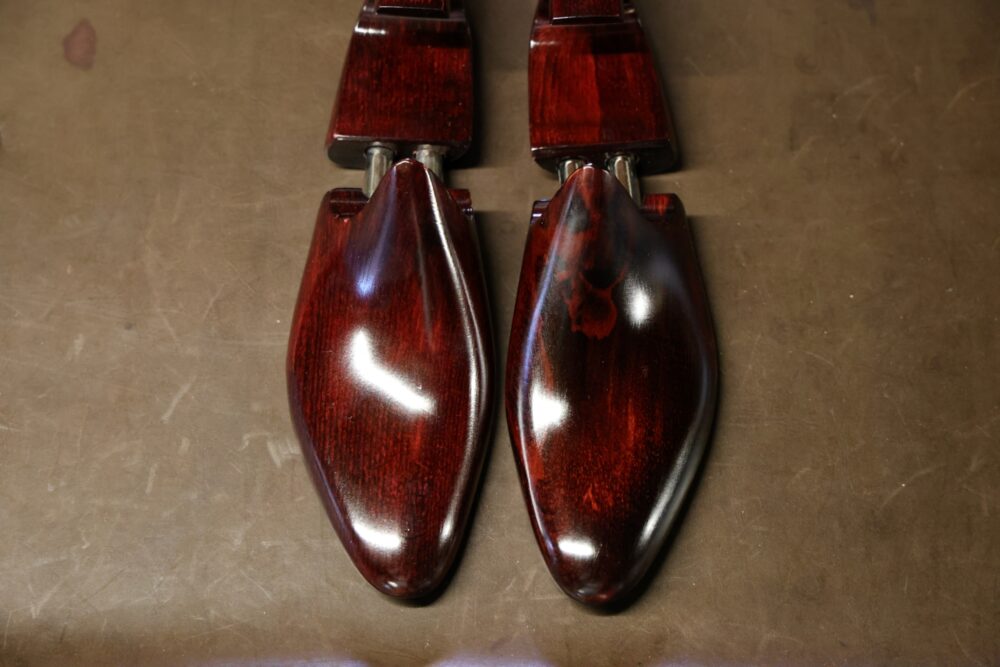A pair of polished wooden shoe trees in a rich mahogany color.