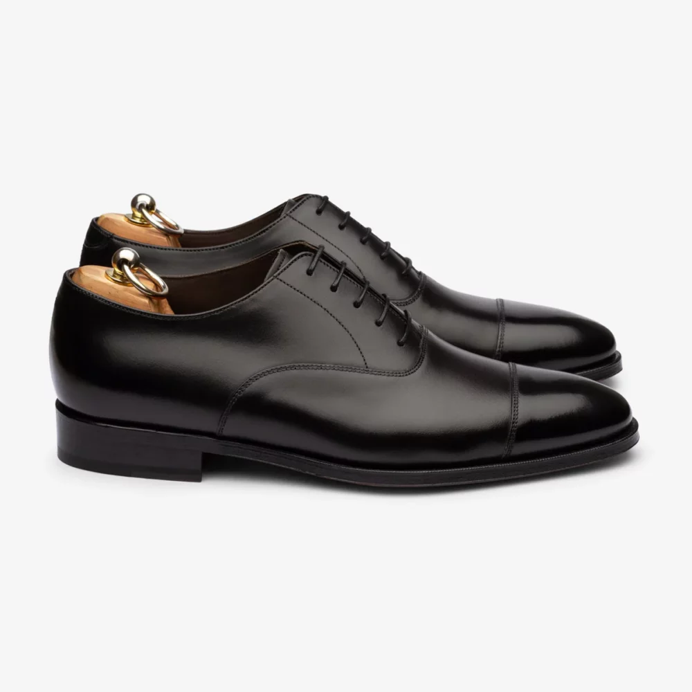 A pair of polished black leather dress shoes with a rounded toe and laces.