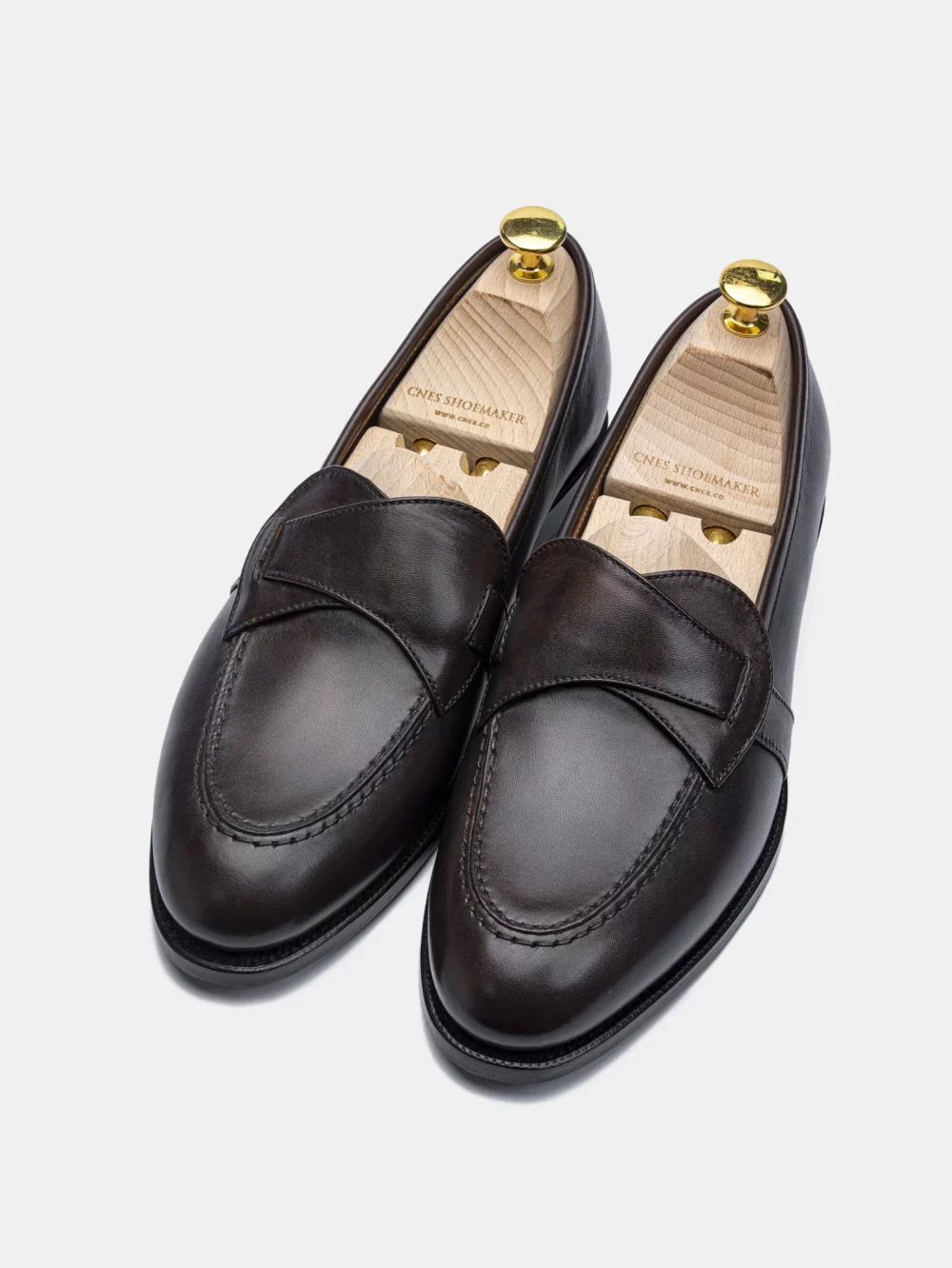 A pair of dark brown leather loafers with wooden shoe trees inside.