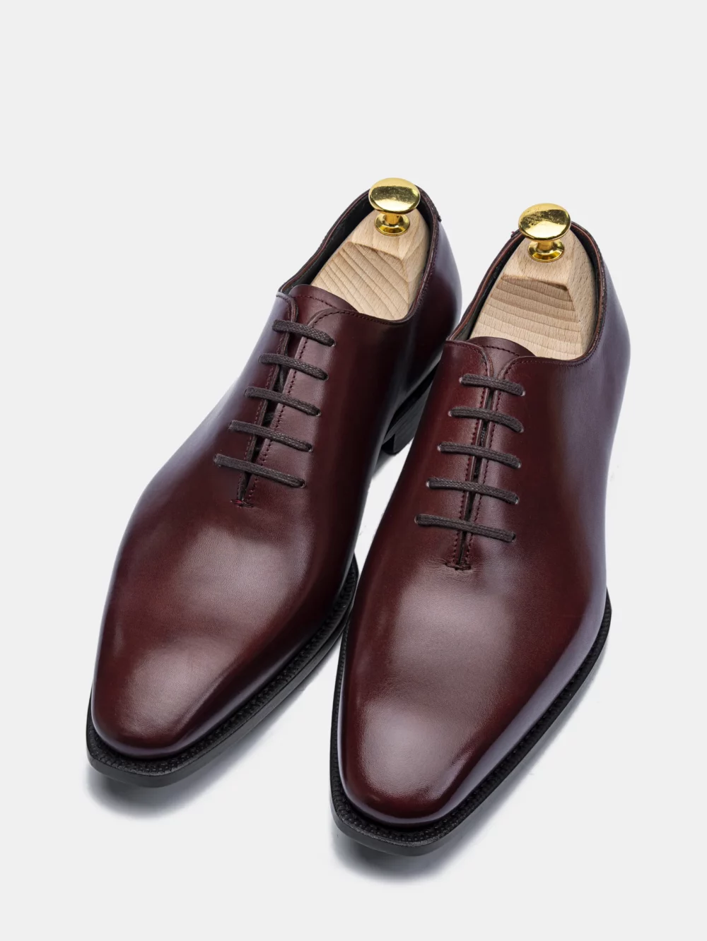 A pair of polished burgundy leather dress shoes with black soles and lace-up closures.