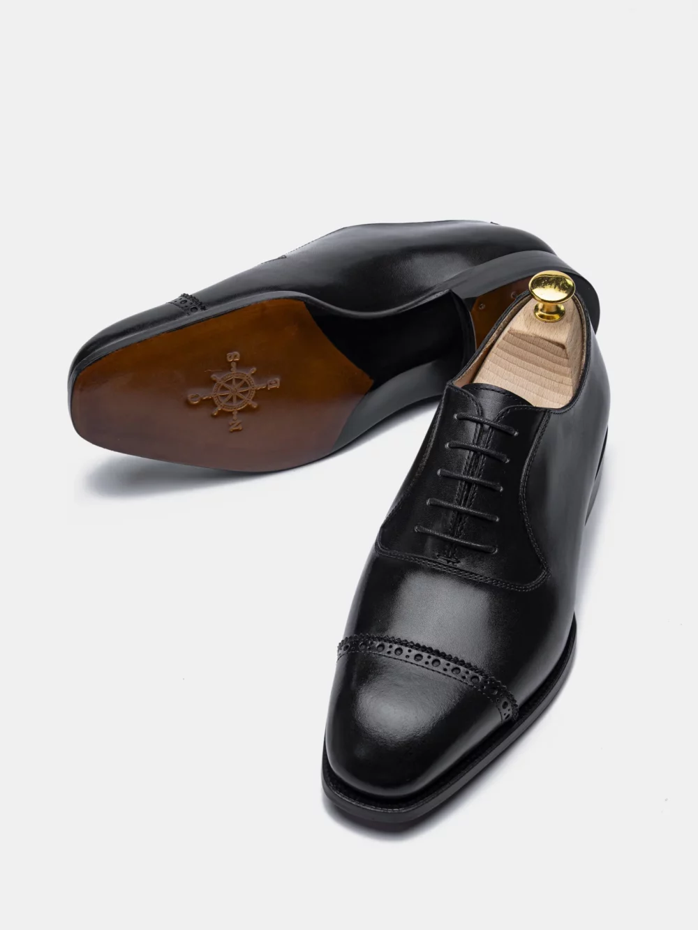 A pair of black leather dress shoes with a lace-up design and decorative brogue detailing.