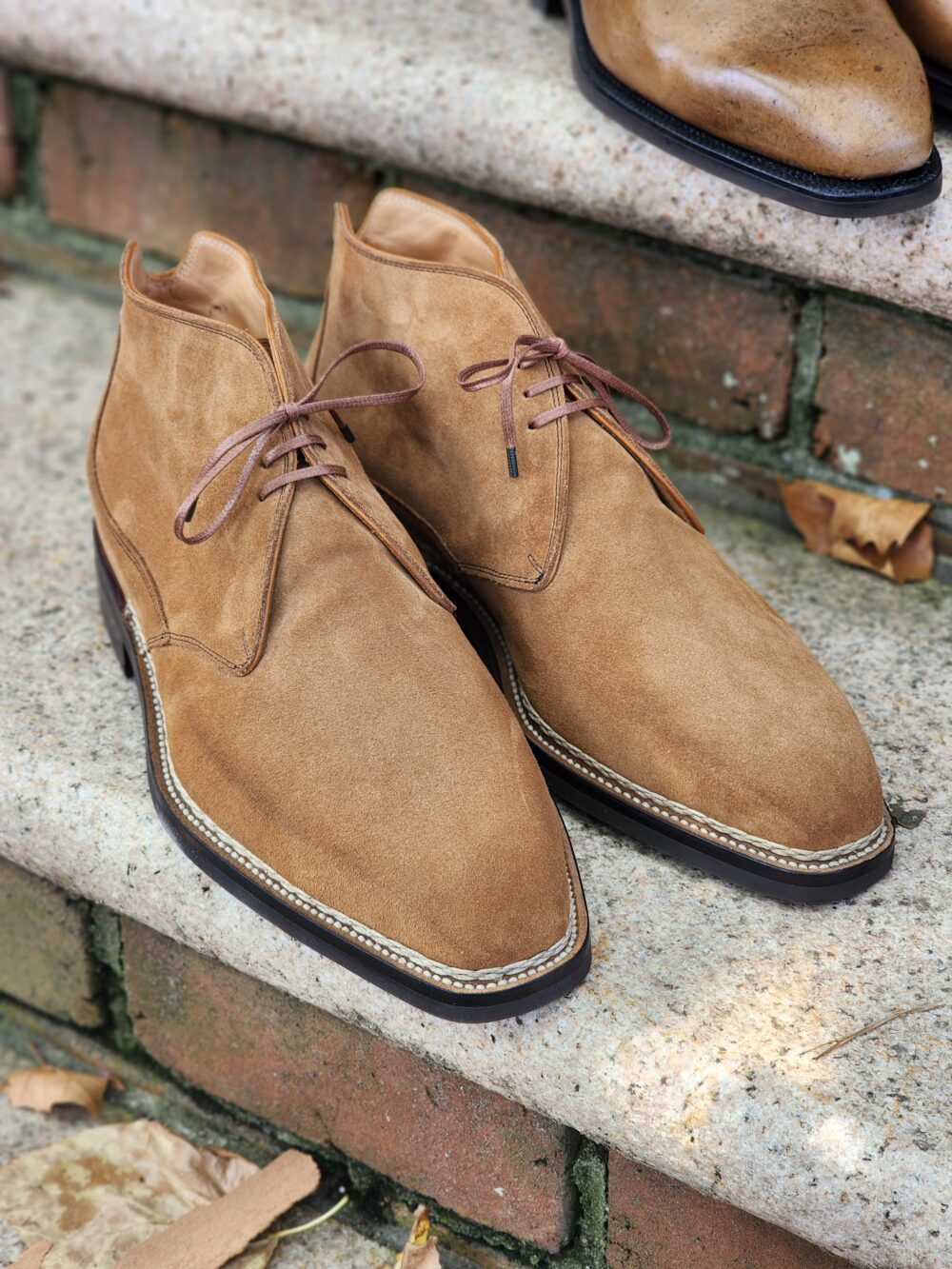 A pair of tan suede ankle boots with brown laces.