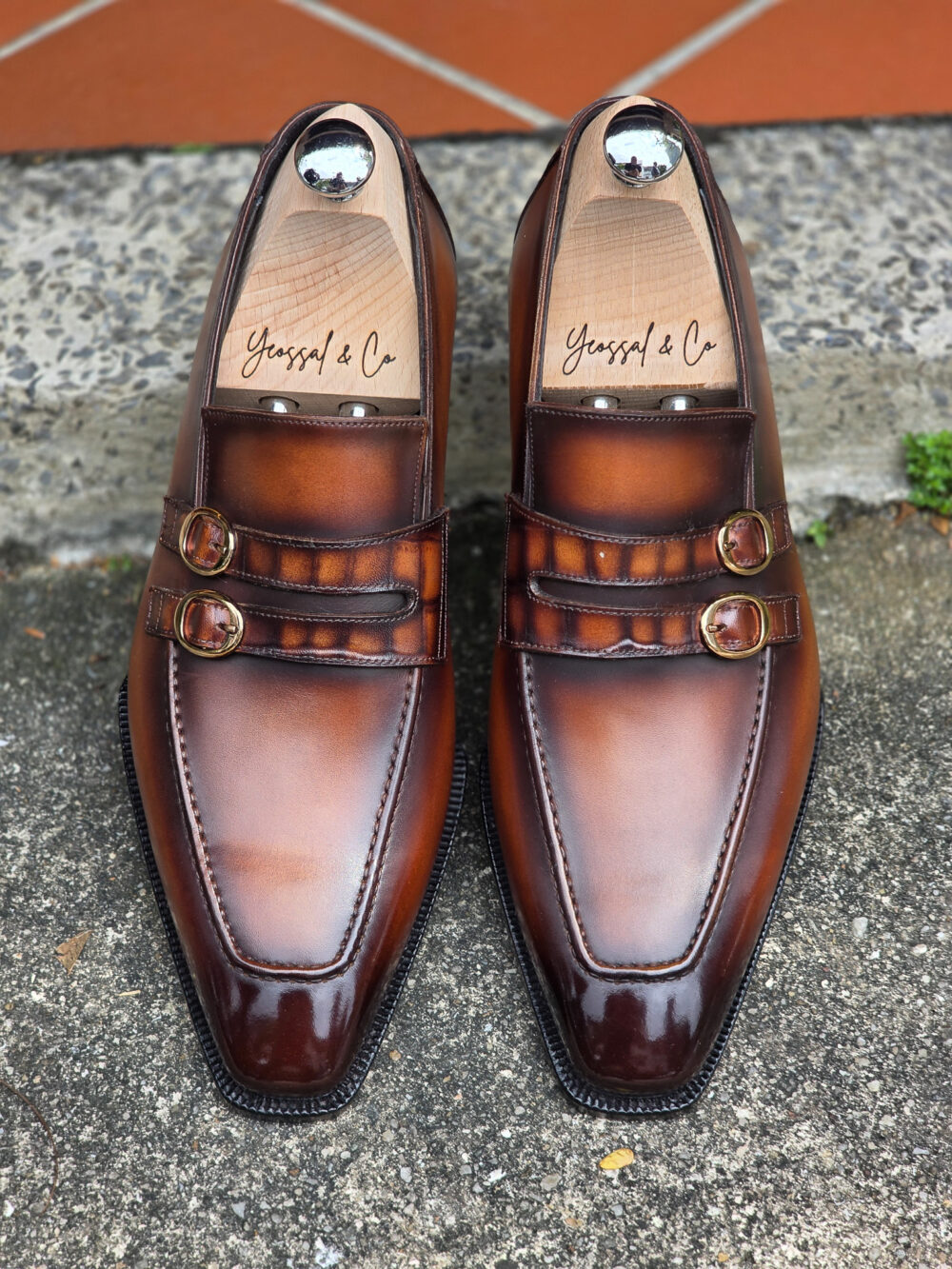 A pair of polished brown leather Yeossal with double buckles and wooden shoe trees inside.