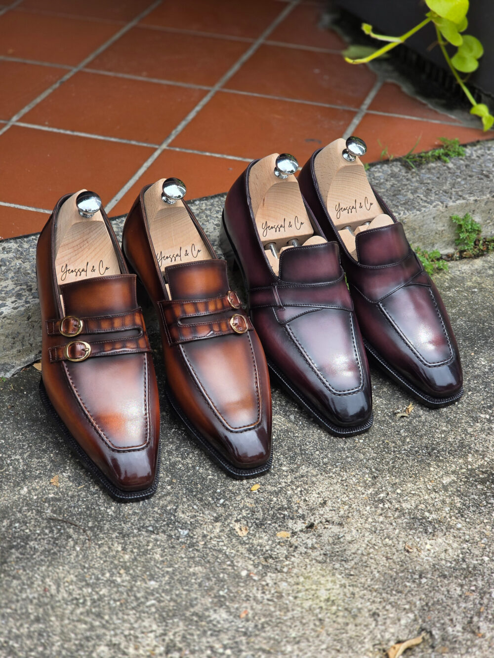 A pair of brown and burgundy leather loafers with decorative buckles, displayed side by side.