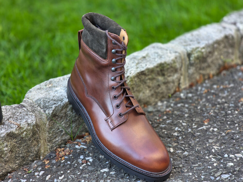 A brown leather boot with a suede collar and black rubber sole.