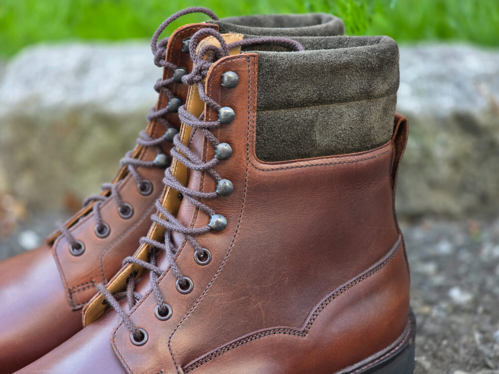 Brown leather boots with a dark green suede collar and metal eyelets.