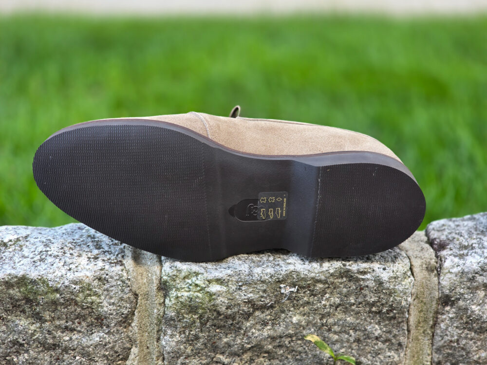 A brown suede shoe sole with a textured black rubber bottom.