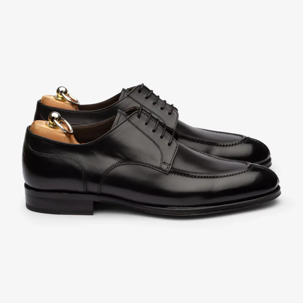 A pair of polished black leather dress shoes with decorative stitching and shoe trees inside.