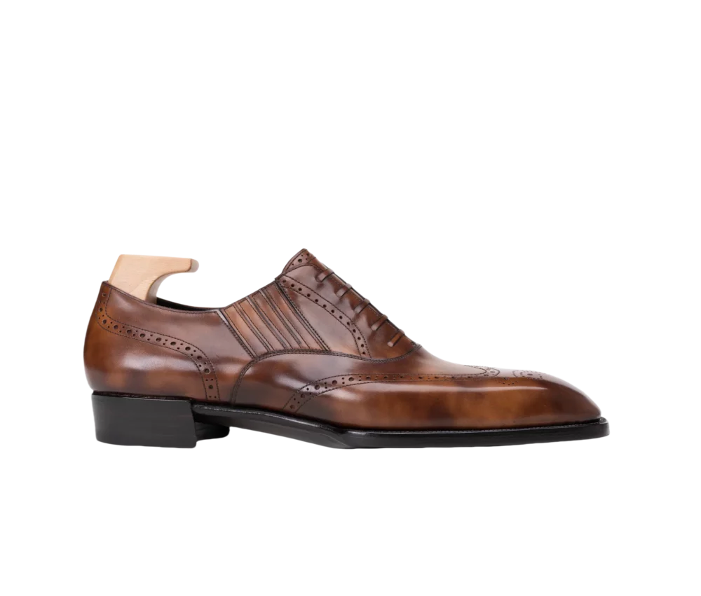 A polished brown leather dress shoe with decorative perforations and a sleek silhouette.