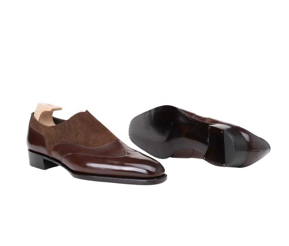 A pair of brown leather dress shoes with a suede upper and a low heel.