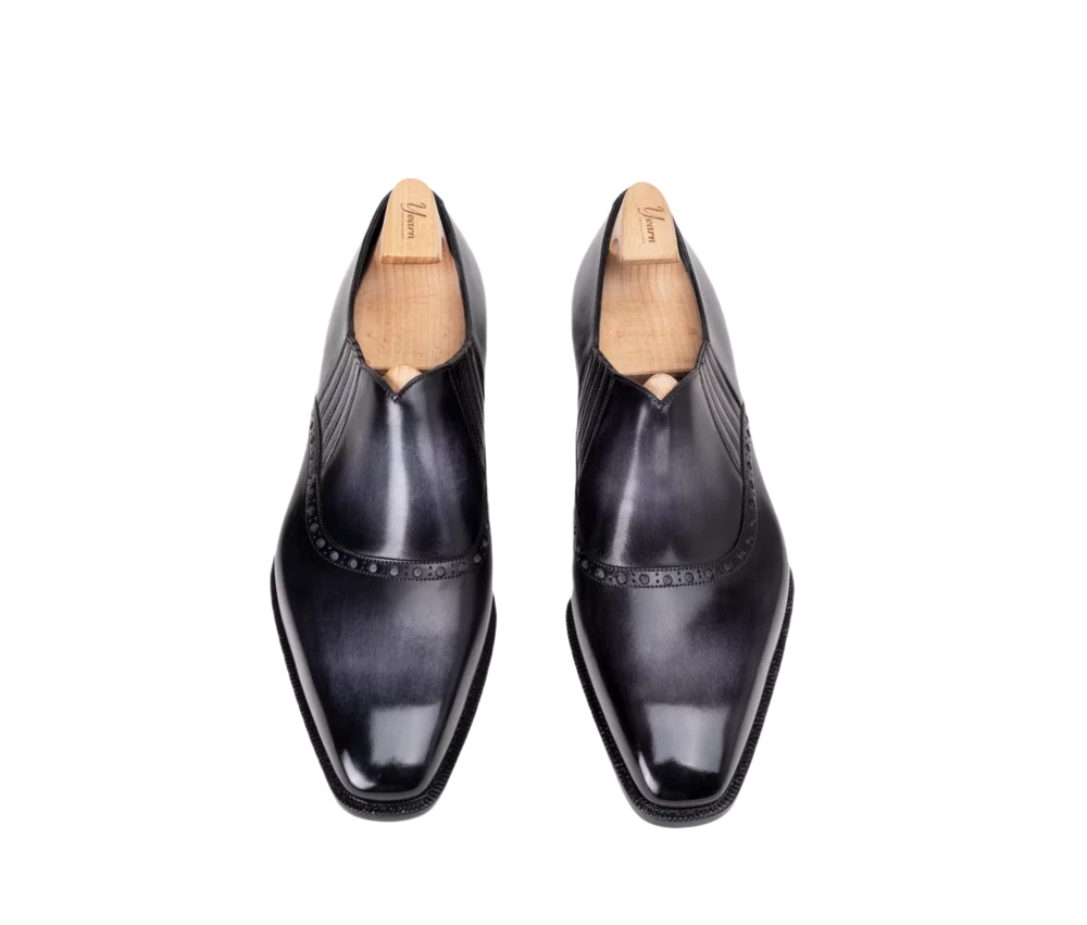 A pair of black leather dress shoes with a sleek design and decorative stitching along the edges.