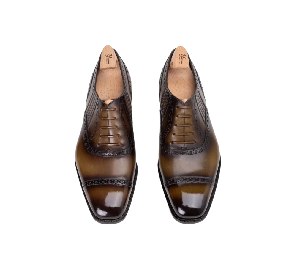 A pair of polished brown leather dress shoes with a lace-up design and decorative stitching.