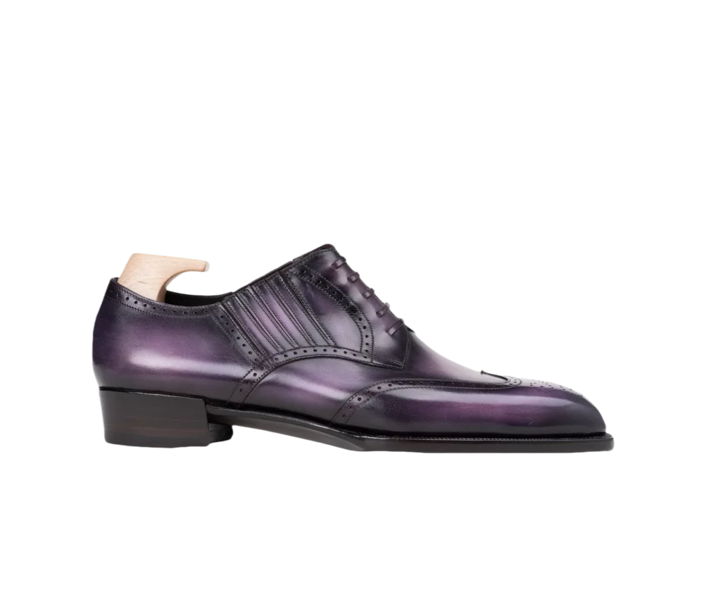A polished leather shoe in gradient shades of purple with decorative perforations and a low heel.
