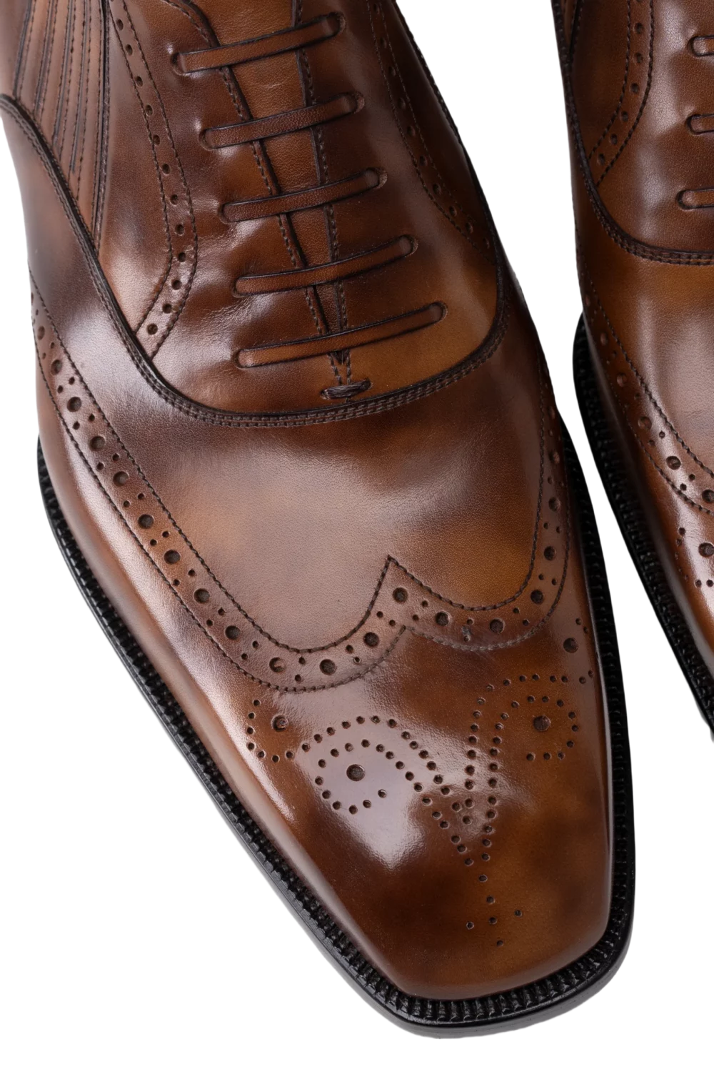A pair of polished brown leather dress shoes with decorative brogue detailing and laces.